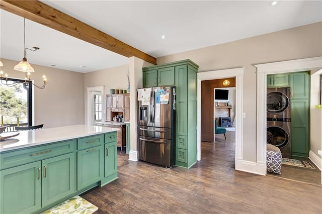 kitchen with stainless steel fridge, stacked washer / dryer, light countertops, green cabinets, and beam ceiling