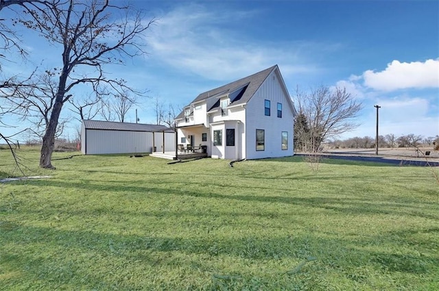 rear view of house featuring a lawn and an outdoor structure