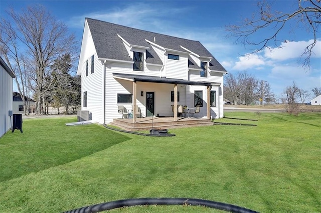 back of property featuring a deck, roof with shingles, a lawn, and central air condition unit