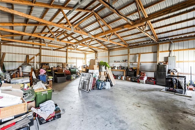 garage with freestanding refrigerator, electric panel, and metal wall