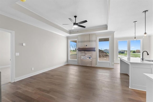 unfurnished living room featuring plenty of natural light, a tray ceiling, and a sink