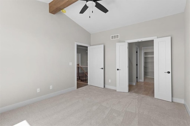 unfurnished bedroom featuring a ceiling fan, lofted ceiling with beams, carpet floors, baseboards, and visible vents
