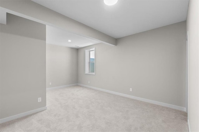 basement featuring light colored carpet and baseboards