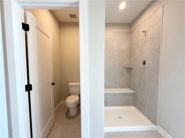 full bath featuring tile patterned flooring, toilet, visible vents, baseboards, and tiled shower