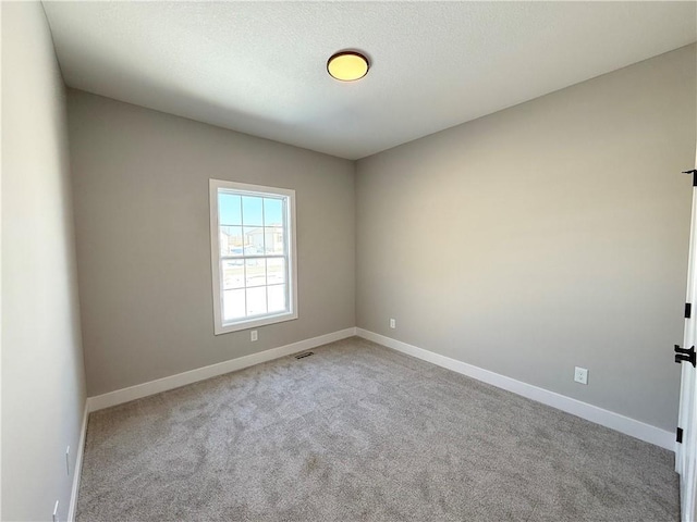 spare room with light carpet, visible vents, baseboards, and a textured ceiling