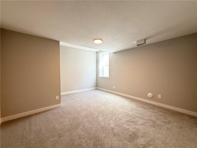 carpeted empty room with a textured ceiling and baseboards