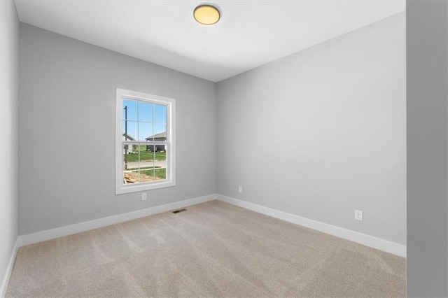 empty room featuring baseboards, visible vents, and carpet