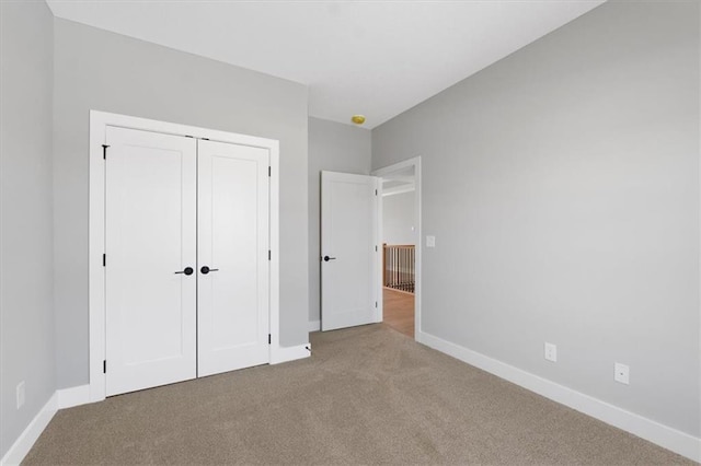 unfurnished bedroom featuring baseboards, carpet, and a closet