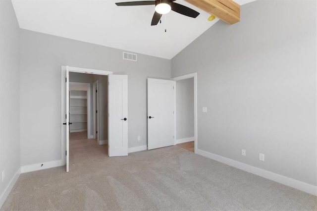 unfurnished bedroom featuring baseboards, visible vents, lofted ceiling with beams, and carpet