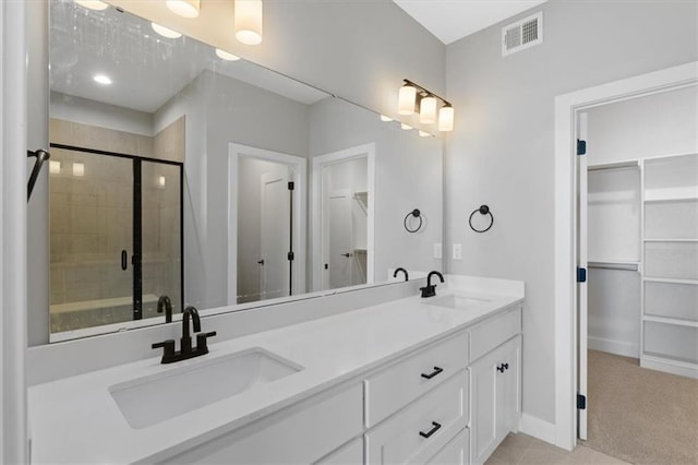 bathroom featuring visible vents, a sink, a spacious closet, and a stall shower