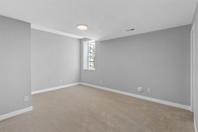 spare room featuring baseboards, a textured ceiling, carpet, and visible vents