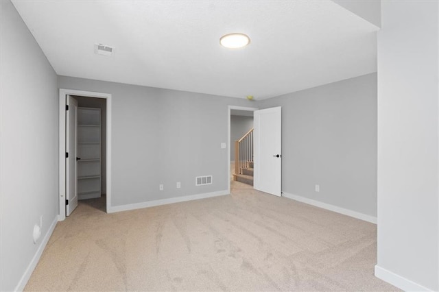spare room featuring baseboards, visible vents, and light carpet