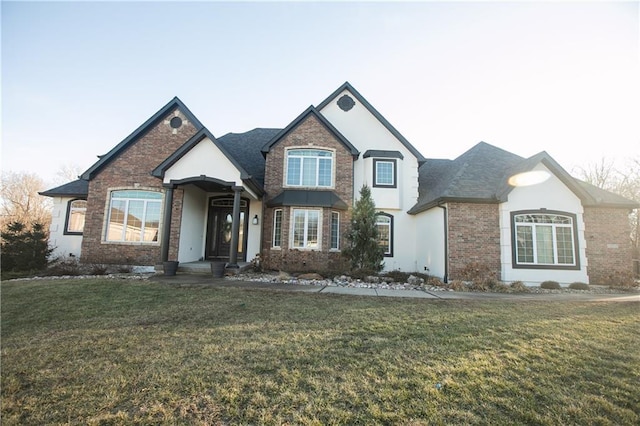 view of front of home featuring a front yard, brick siding, and roof with shingles