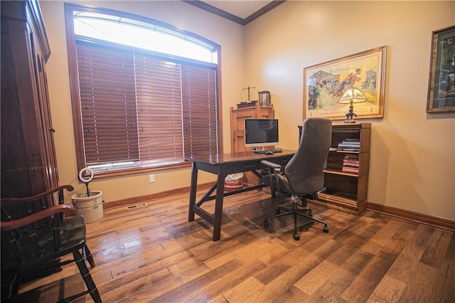 office featuring ornamental molding, wood-type flooring, visible vents, and baseboards