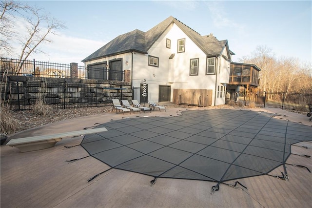 rear view of house featuring a fenced in pool, a patio area, fence, and stucco siding