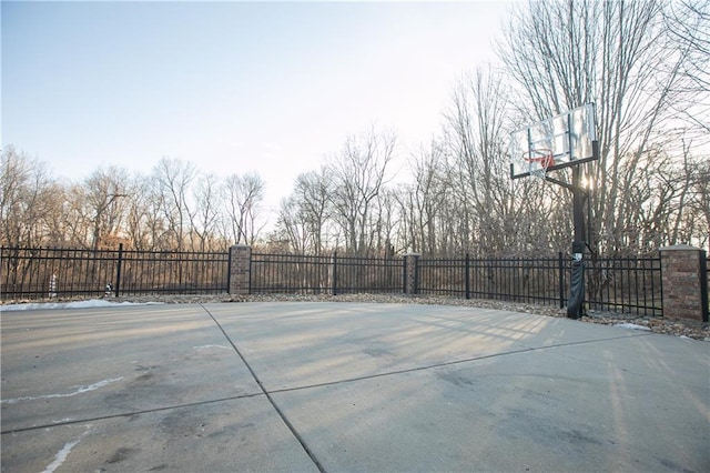view of basketball court featuring basketball hoop and fence