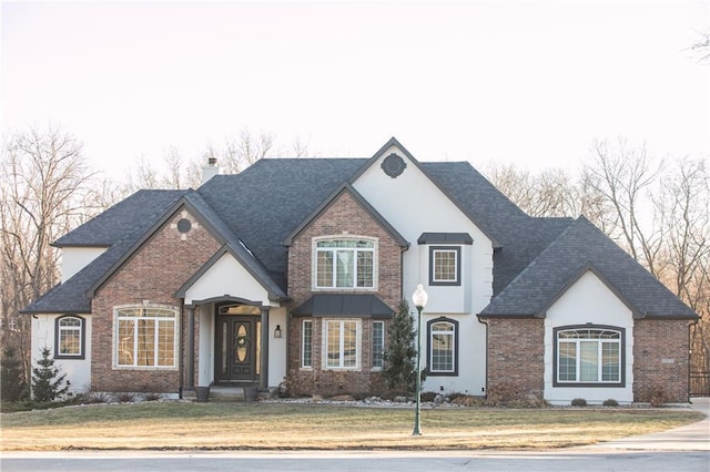 view of front of property with a front yard, brick siding, a chimney, and roof with shingles