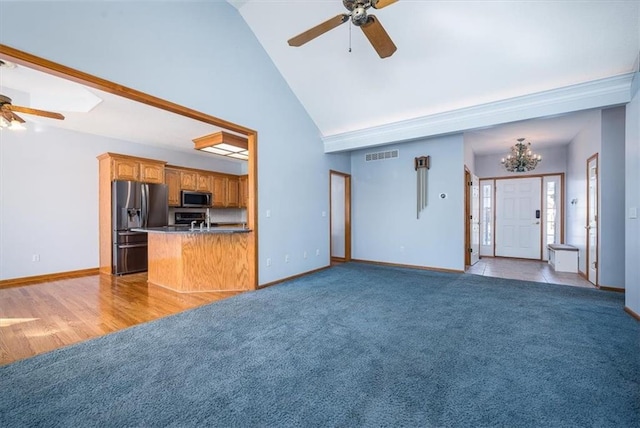 unfurnished living room with visible vents, baseboards, light colored carpet, high vaulted ceiling, and ceiling fan with notable chandelier