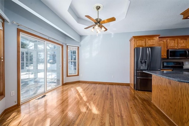 kitchen with visible vents, brown cabinetry, electric range oven, black fridge with ice dispenser, and a tray ceiling