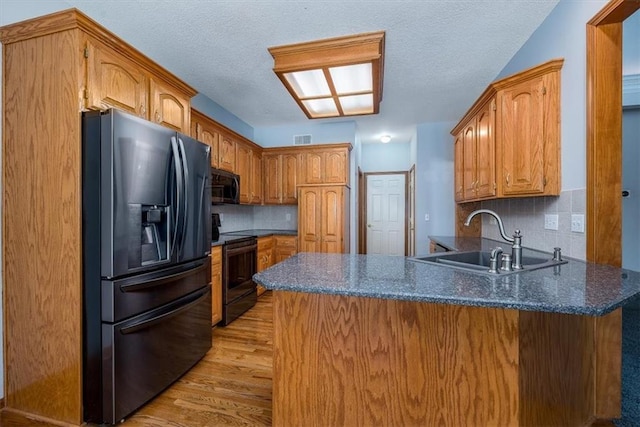 kitchen featuring electric stove, a sink, stainless steel refrigerator with ice dispenser, and a peninsula