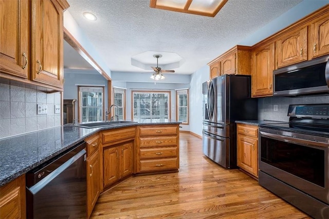 kitchen with brown cabinets, light wood-style floors, ceiling fan, and stainless steel appliances