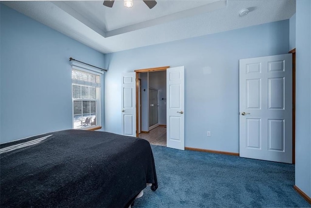 unfurnished bedroom with ceiling fan, carpet floors, a raised ceiling, and baseboards