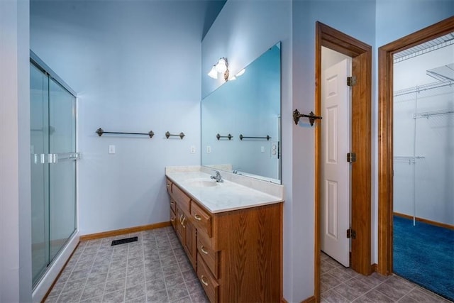 bathroom featuring a stall shower, visible vents, baseboards, and vanity