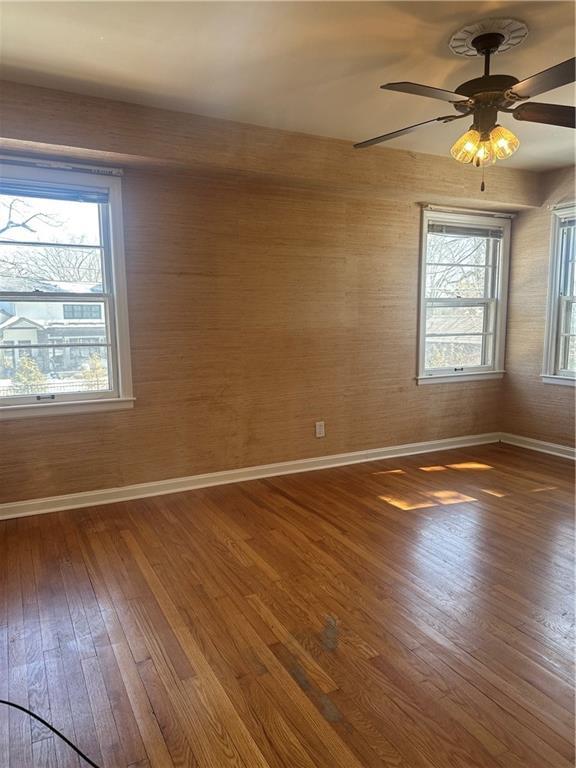 spare room with a ceiling fan, baseboards, and wood finished floors