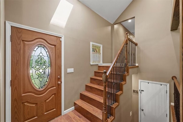 foyer featuring lofted ceiling, wood finished floors, baseboards, and stairs