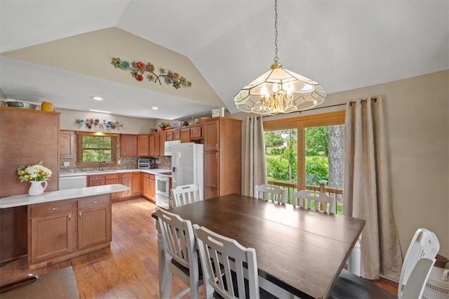 dining room featuring lofted ceiling, light wood finished floors, and a chandelier