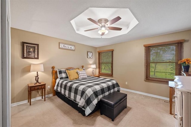 bedroom with light carpet, a tray ceiling, a textured ceiling, and baseboards