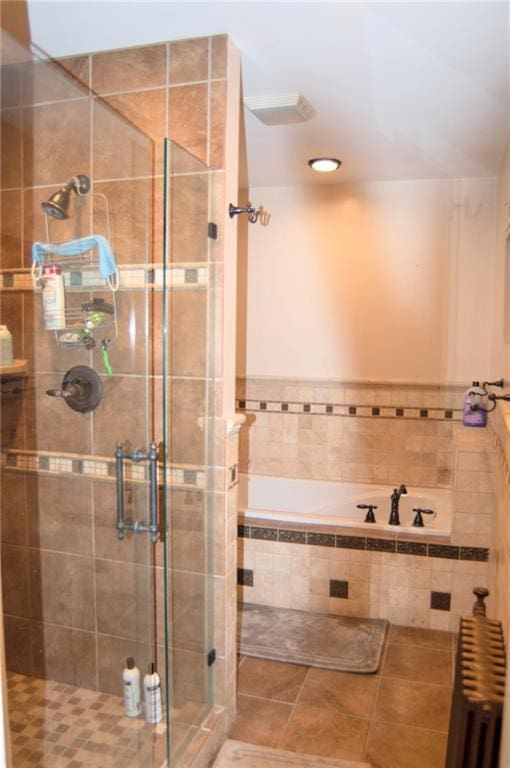 bathroom with a stall shower, radiator heating unit, a bath, and tile patterned floors