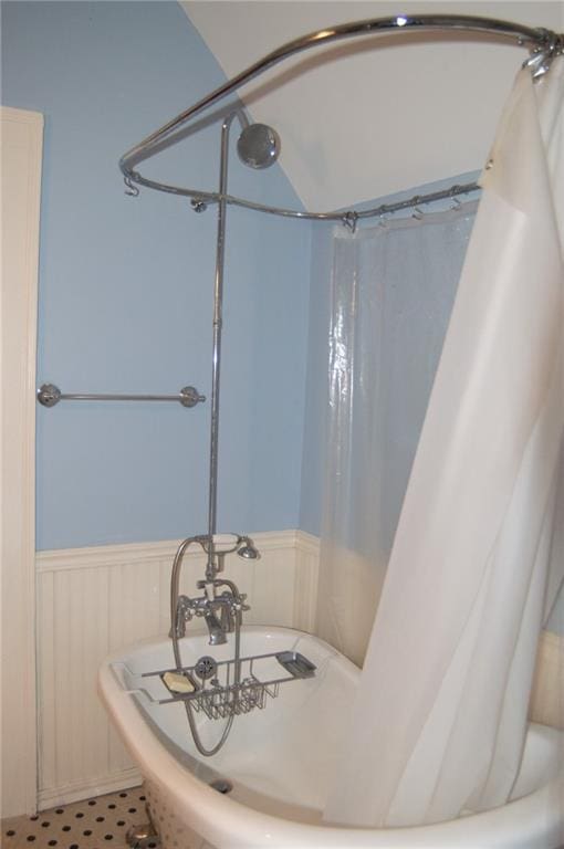 bathroom with a wainscoted wall and shower / bath combination with curtain