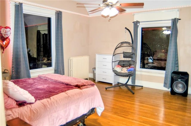 bedroom with radiator, ceiling fan, baseboards, and wood finished floors