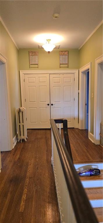 hallway featuring dark wood-type flooring, crown molding, and baseboards