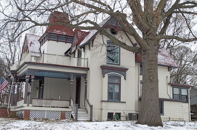 view of front of property with a porch, central AC, brick siding, and a balcony