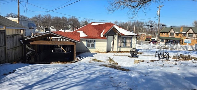 snow covered rear of property featuring a residential view and fence