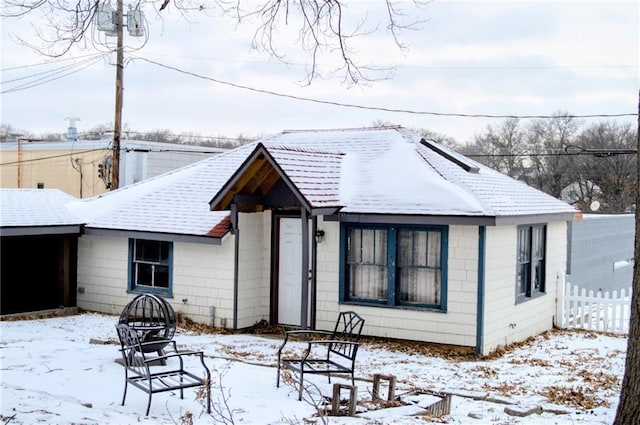 snow covered property with a fire pit and a shingled roof