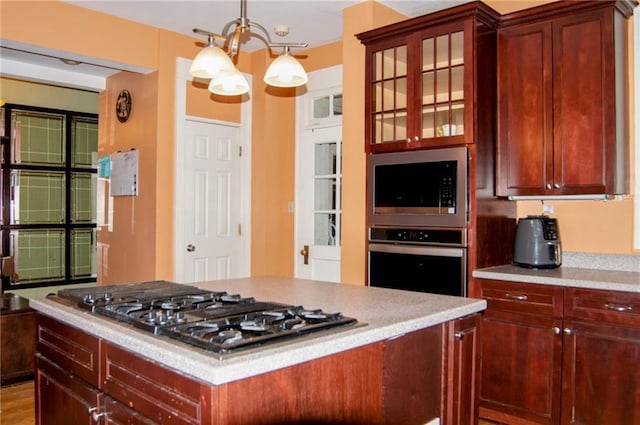 kitchen featuring stainless steel appliances, glass insert cabinets, hanging light fixtures, and dark brown cabinets