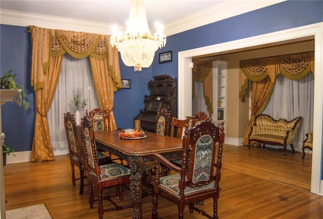 dining area featuring a notable chandelier, baseboards, wood finished floors, and crown molding