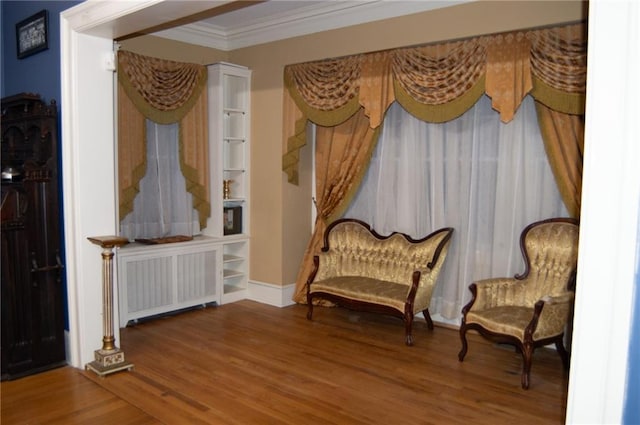 sitting room with ornamental molding, radiator heating unit, and wood finished floors