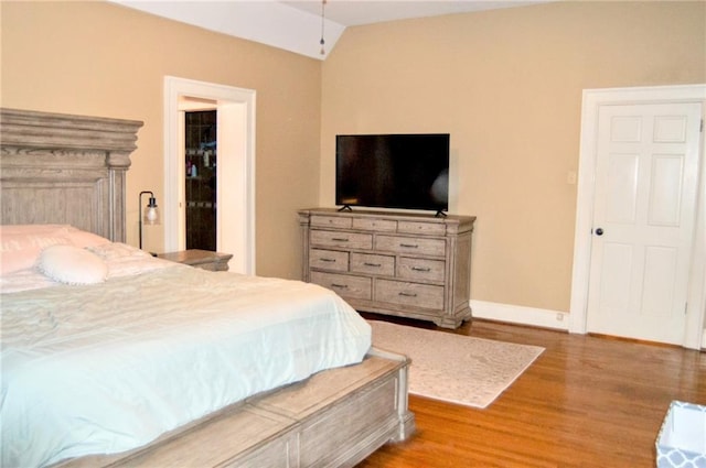 bedroom with light wood-style flooring, baseboards, and vaulted ceiling