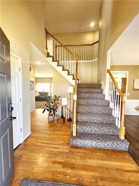 entrance foyer featuring stairway, a towering ceiling, and wood finished floors