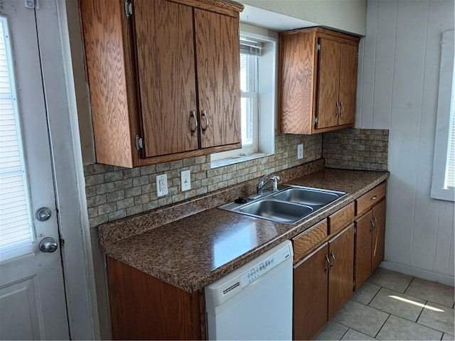 kitchen with dishwasher, backsplash, dark countertops, and a sink