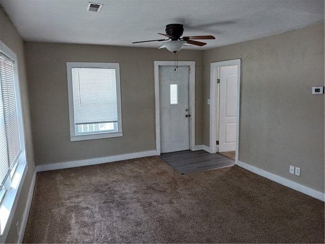 foyer with ceiling fan, visible vents, baseboards, and dark colored carpet