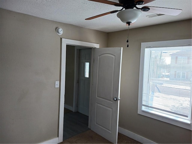 interior space with baseboards, visible vents, ceiling fan, and a textured ceiling