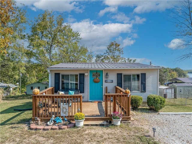 view of front of home featuring metal roof, a front yard, and a wooden deck