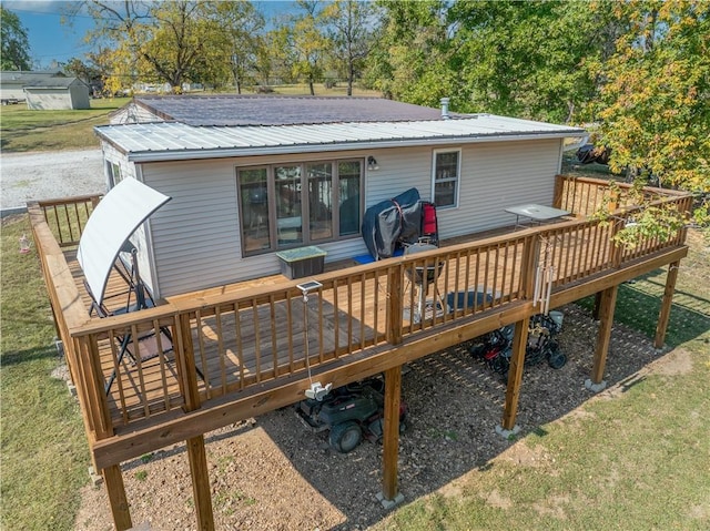 rear view of property featuring metal roof, a lawn, and a wooden deck