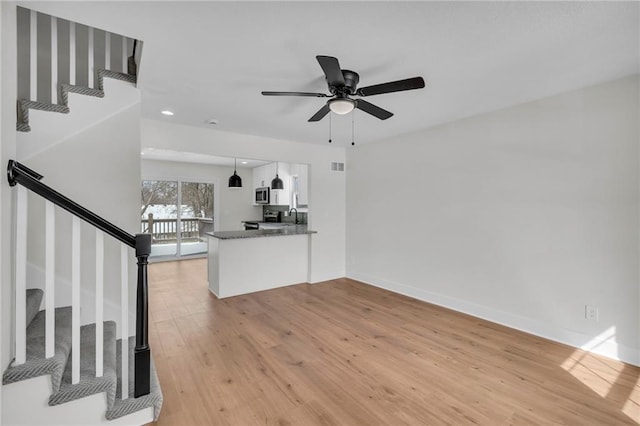 unfurnished living room featuring recessed lighting, a ceiling fan, baseboards, light wood-style floors, and stairway