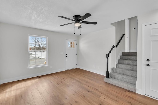 entryway featuring wood-type flooring, visible vents, a ceiling fan, baseboards, and stairs